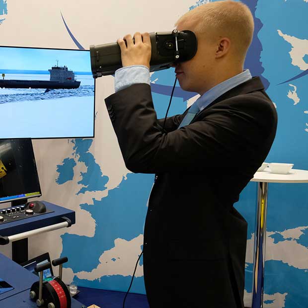 Man with VR glasses standing in front of a wall of monitors